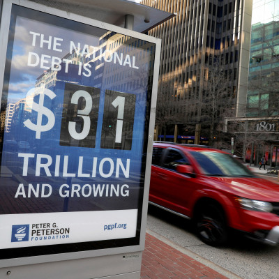 ワシントン州のバス停で、米国の国家債務額を示すボードの横を車が走る