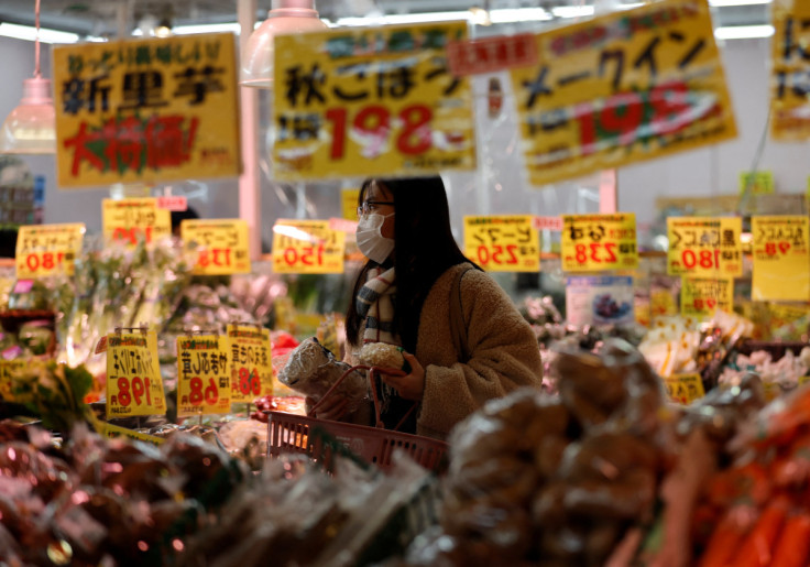 東京のスーパーで食料品をチェックする買物客が鏡のガラスに映る