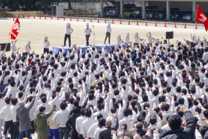 トヨタ自動車の労働組合のメンバーは、豊田市の会社本社で毎年恒例の「春闘」賃金交渉の集会でスローガンを叫びながら拳を上げます。