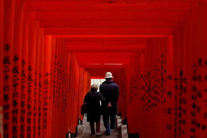 新型コロナウイルス感染症（COVID-19）が流行する東京の神社で、赤い木製の鳥居を歩く老夫婦