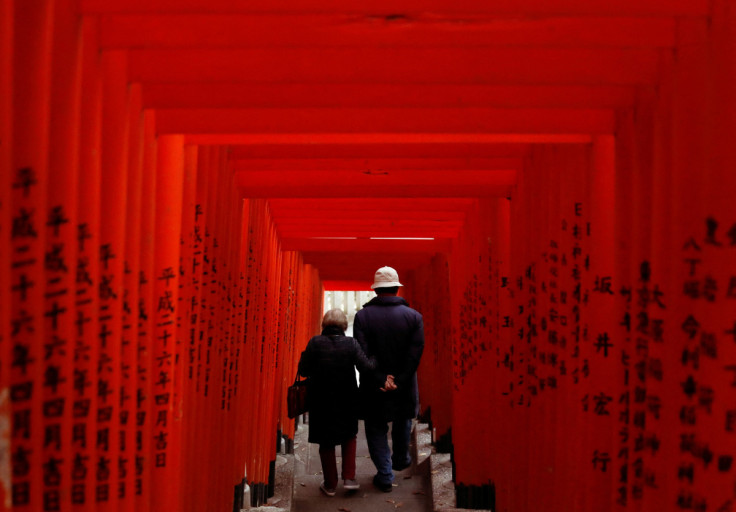 新型コロナウイルス感染症（COVID-19）が流行する東京の神社で、赤い木製の鳥居を歩く老夫婦