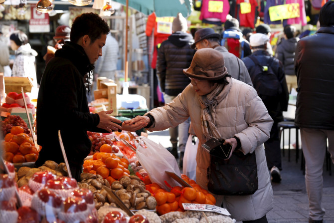 東京のアメ横商店街の八百屋の外で果物を買いながらお金を払う女性