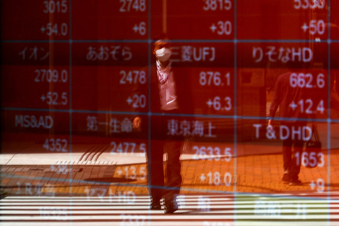 東京の証券会社の外の電光掲示板に映る男性