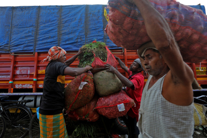 ムンバイの青果卸売市場で自転車に野菜を積み込む労働者