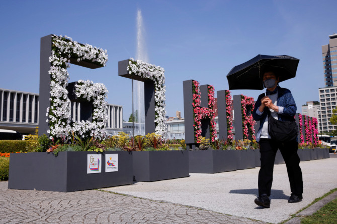 広島でG7サミットを前に、平和記念資料館近くの「G7ヒロシマ」の花のインスタレーションの前を歩く女性。