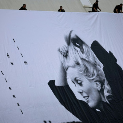 フランスのカトリーヌ・ドヌーヴをフィーチャーした第76回カンヌ国際映画祭の公式ポスターを設置する労働者