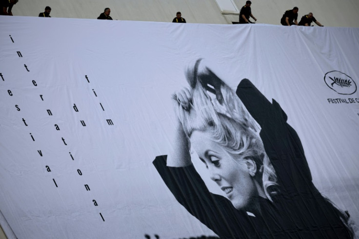 フランスのカトリーヌ・ドヌーヴをフィーチャーした第76回カンヌ国際映画祭の公式ポスターを設置する労働者