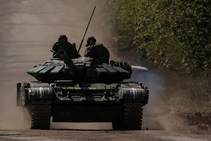 最前線の町バフムートへ向かう道路で戦車の上に乗るウクライナ軍人