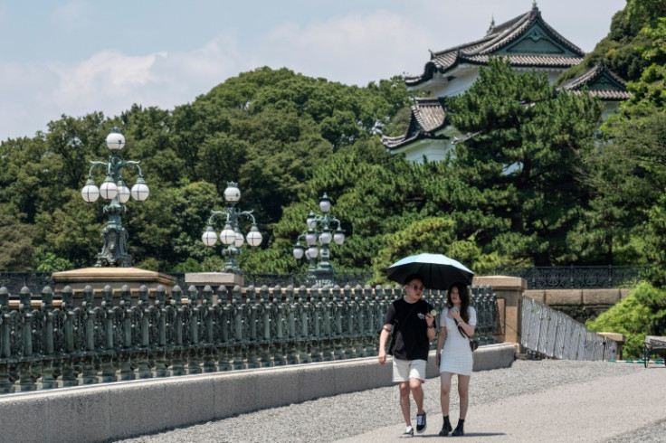 多くの人が傘の下で太陽光線を避けようとしました